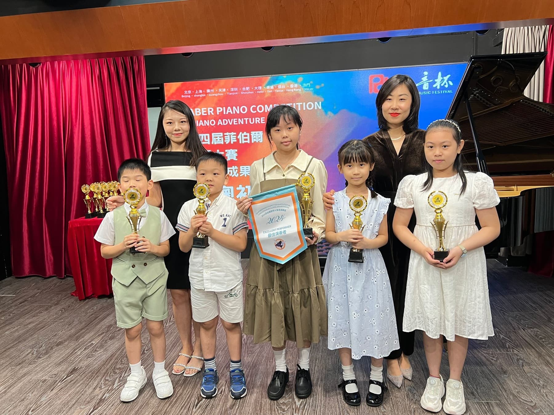 Young pianists and teachers holding trophies after a competition